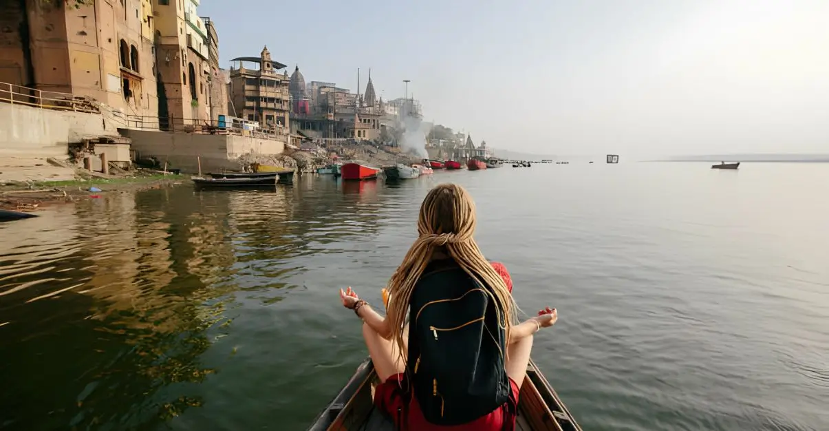 Traveler female wearing dreadlocks seating in wooden boat and enjoy Varanasi