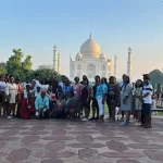 Group of tourists posing in front of the Taj Mahal during a India tour.