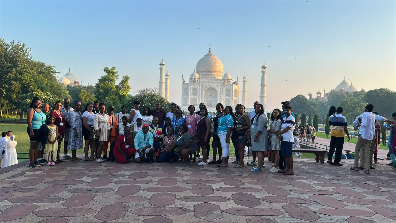 Group of tourists posing in front of the Taj Mahal during a India tour.